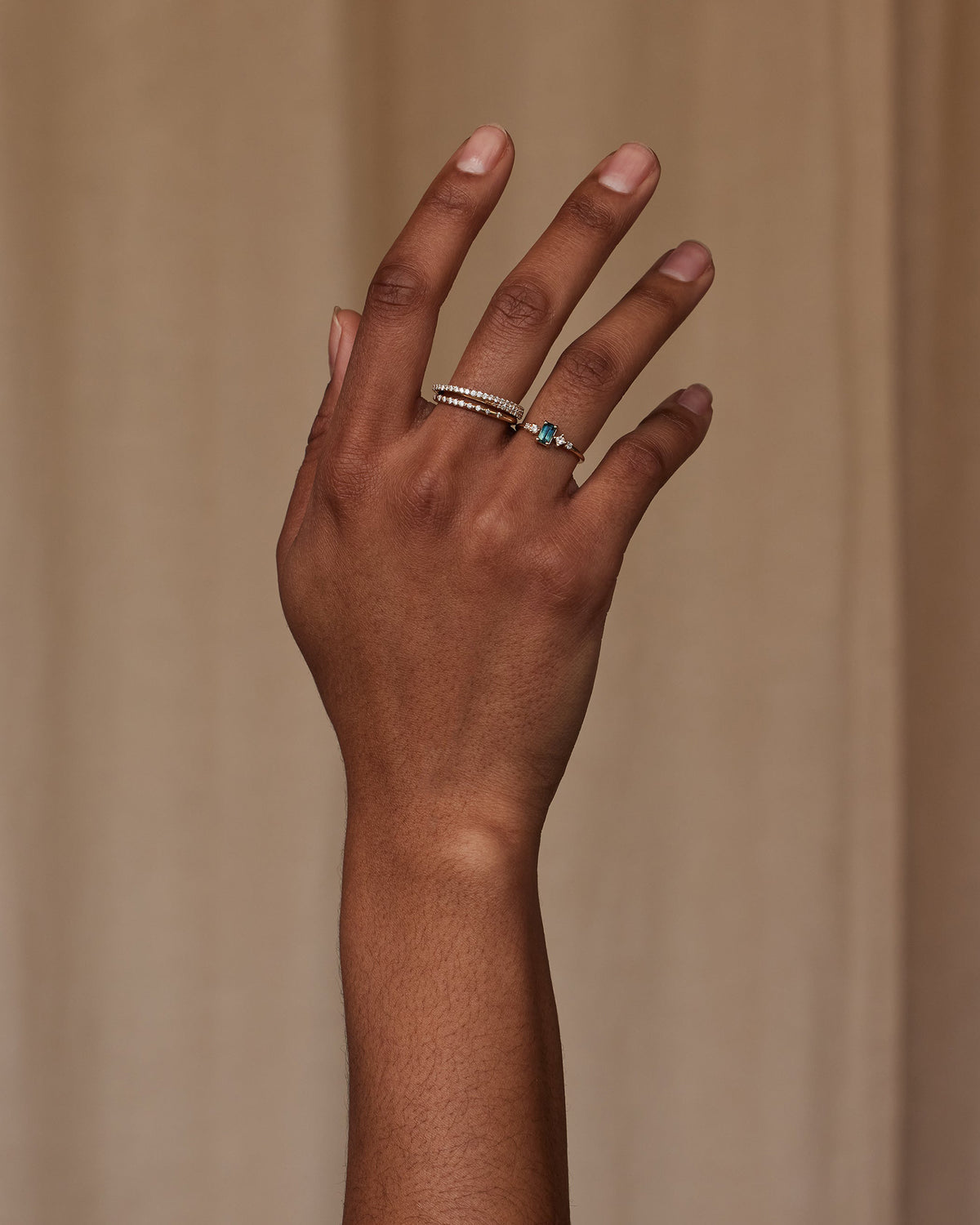 [lifestyle]Hand wearing two rings on a beige background