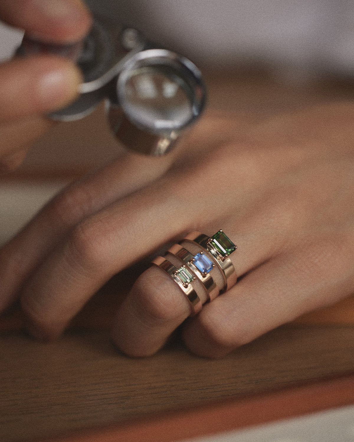 [lifestyle]Close-up of a hand wearing multiple rings with gemstones, held by another hand.