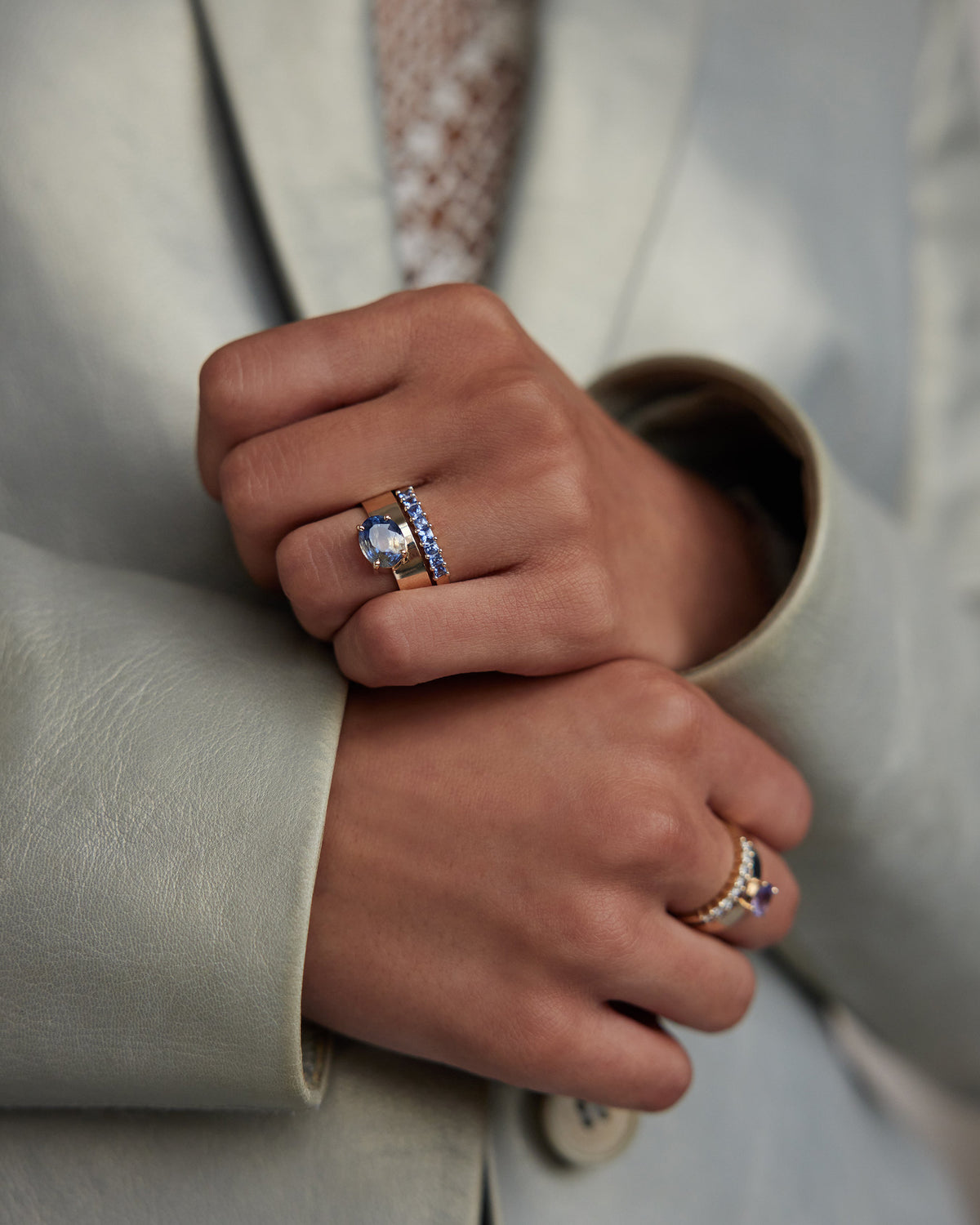 [lifestyle]Close-up of a hand wearing multiple rings with a neutral background