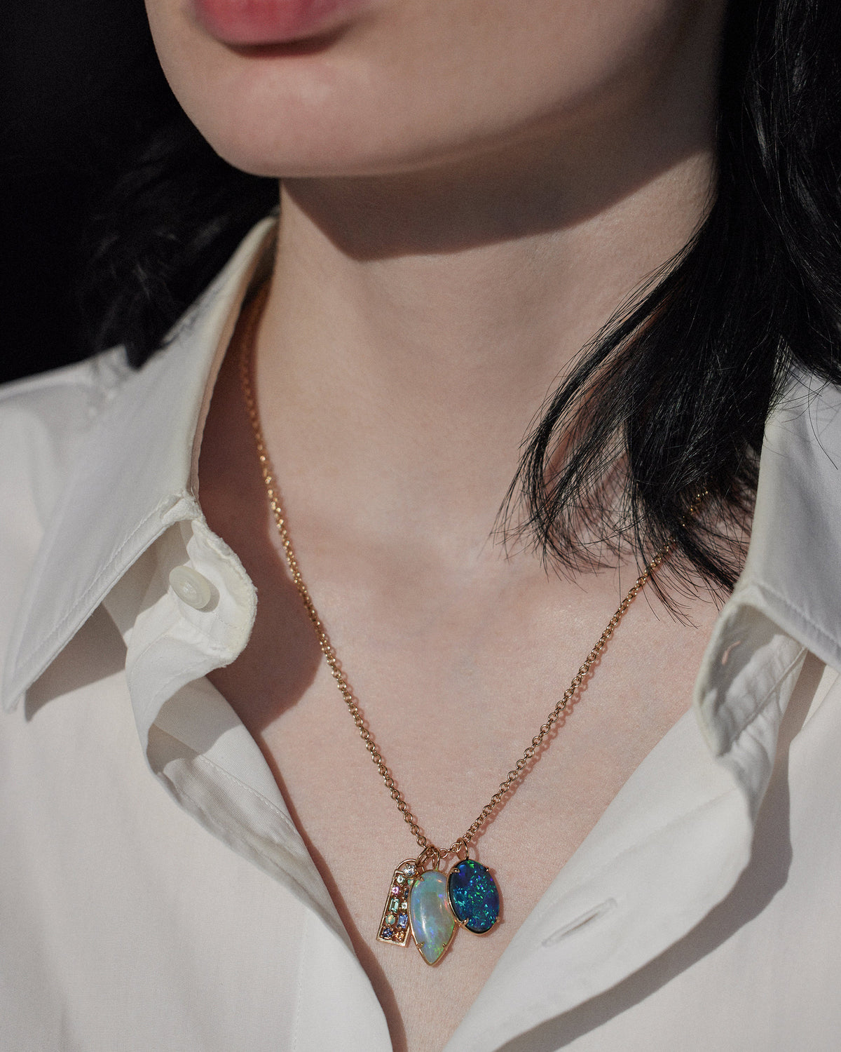 [lifestyle] Necklace with a blue pendant worn by a person in a white shirt.