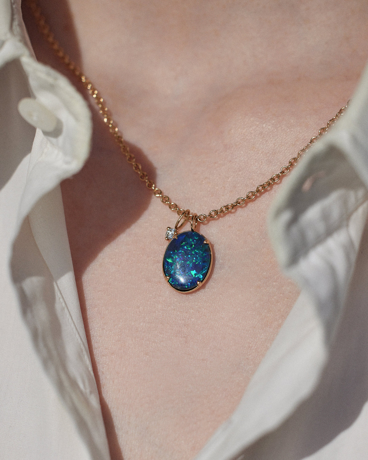 [lifestyle]Necklace with a blue pendant worn by a person, against a neutral background