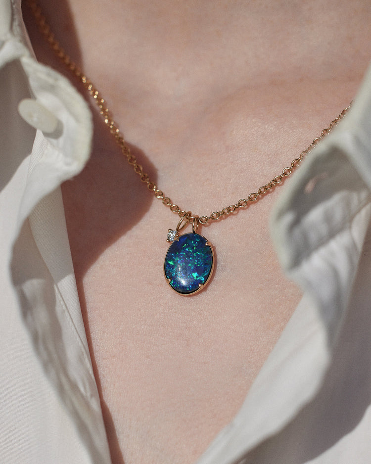 [lifestyle]Necklace with a blue pendant worn by a person, against a neutral background