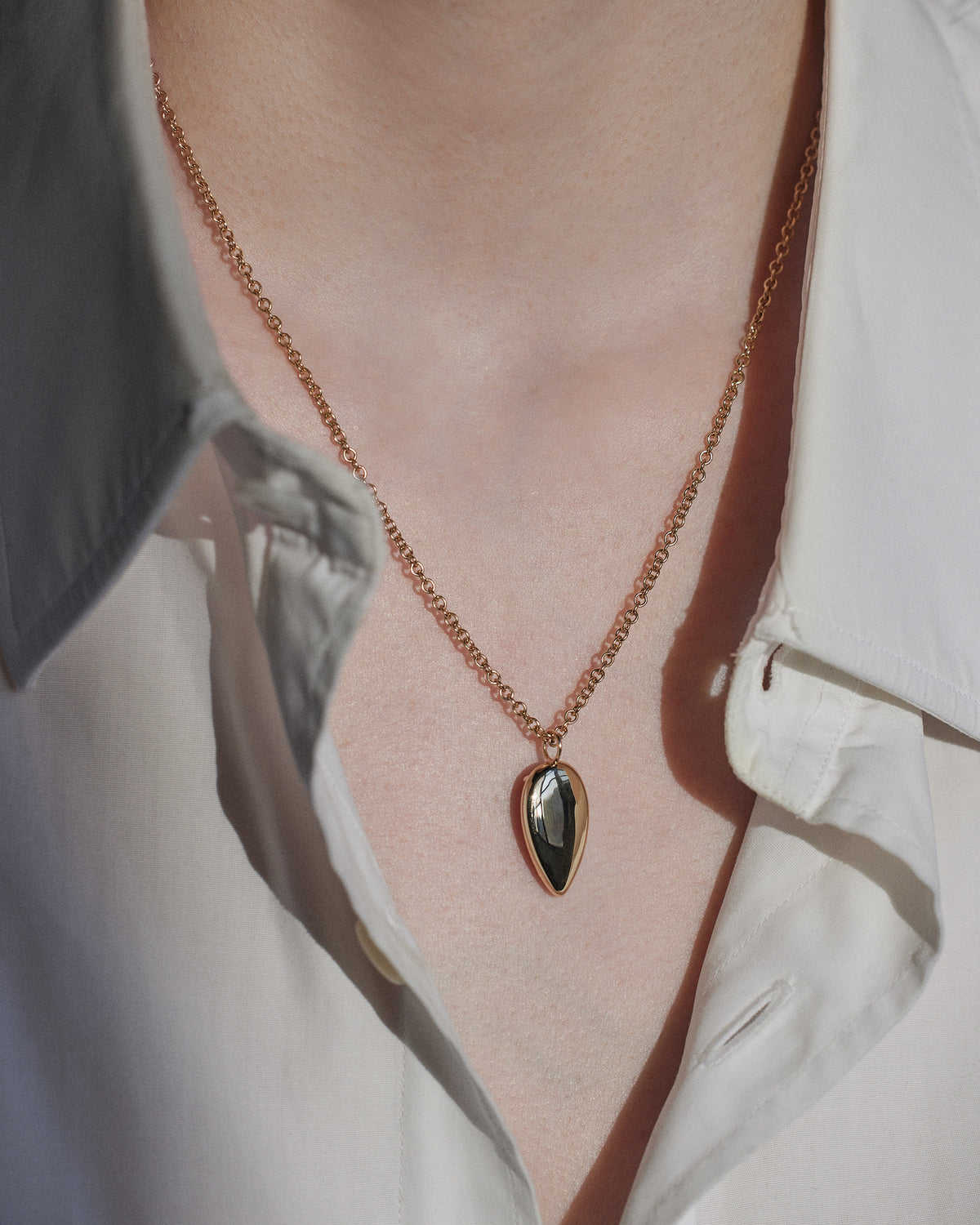 [lifestyle]Necklace with a pendant worn by a person, focusing on the jewelry.