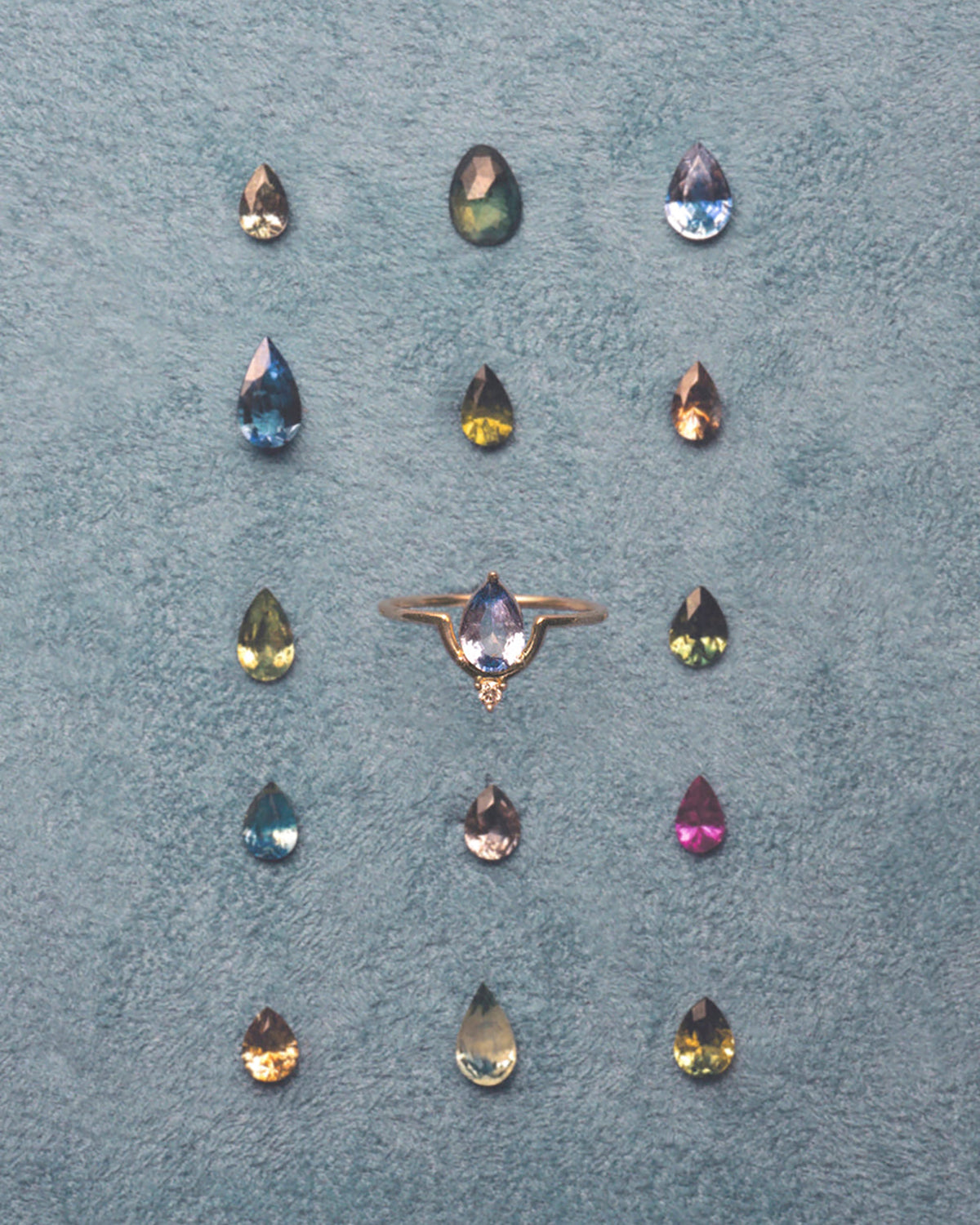 [lifestyle]Ring with multicolored gemstones on a textured blue surface
